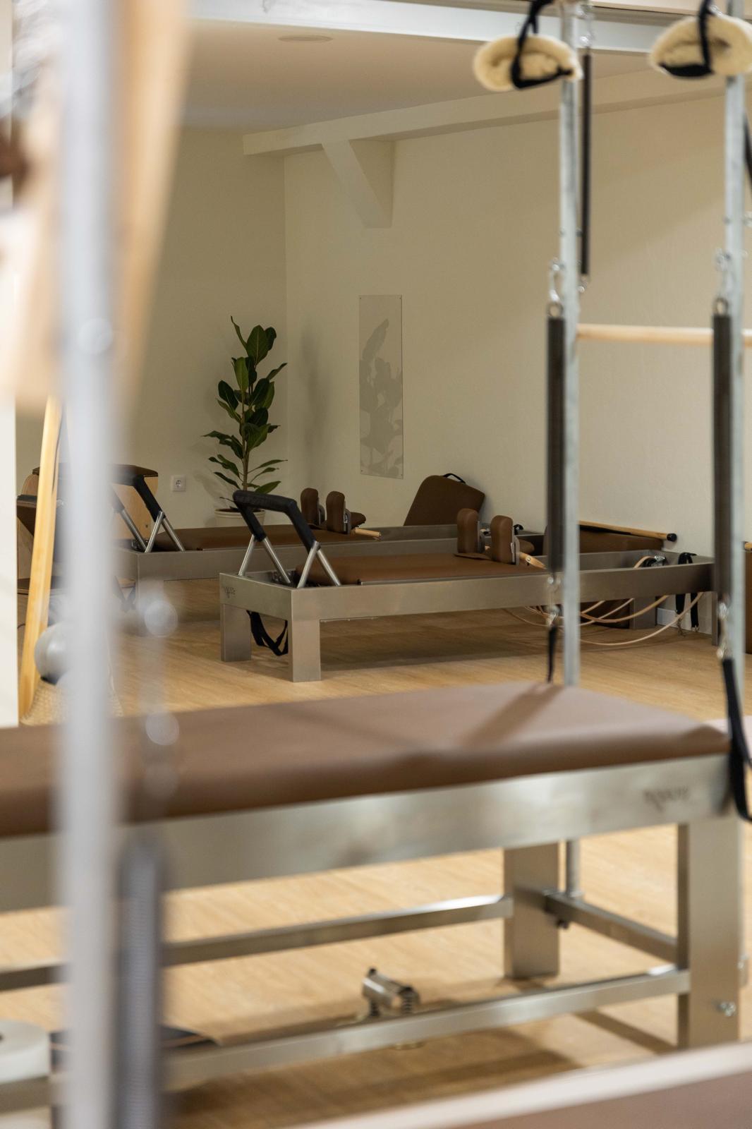 Sala do Core&More Pilates Studio, com Reformers, chão em madeira clara e planta